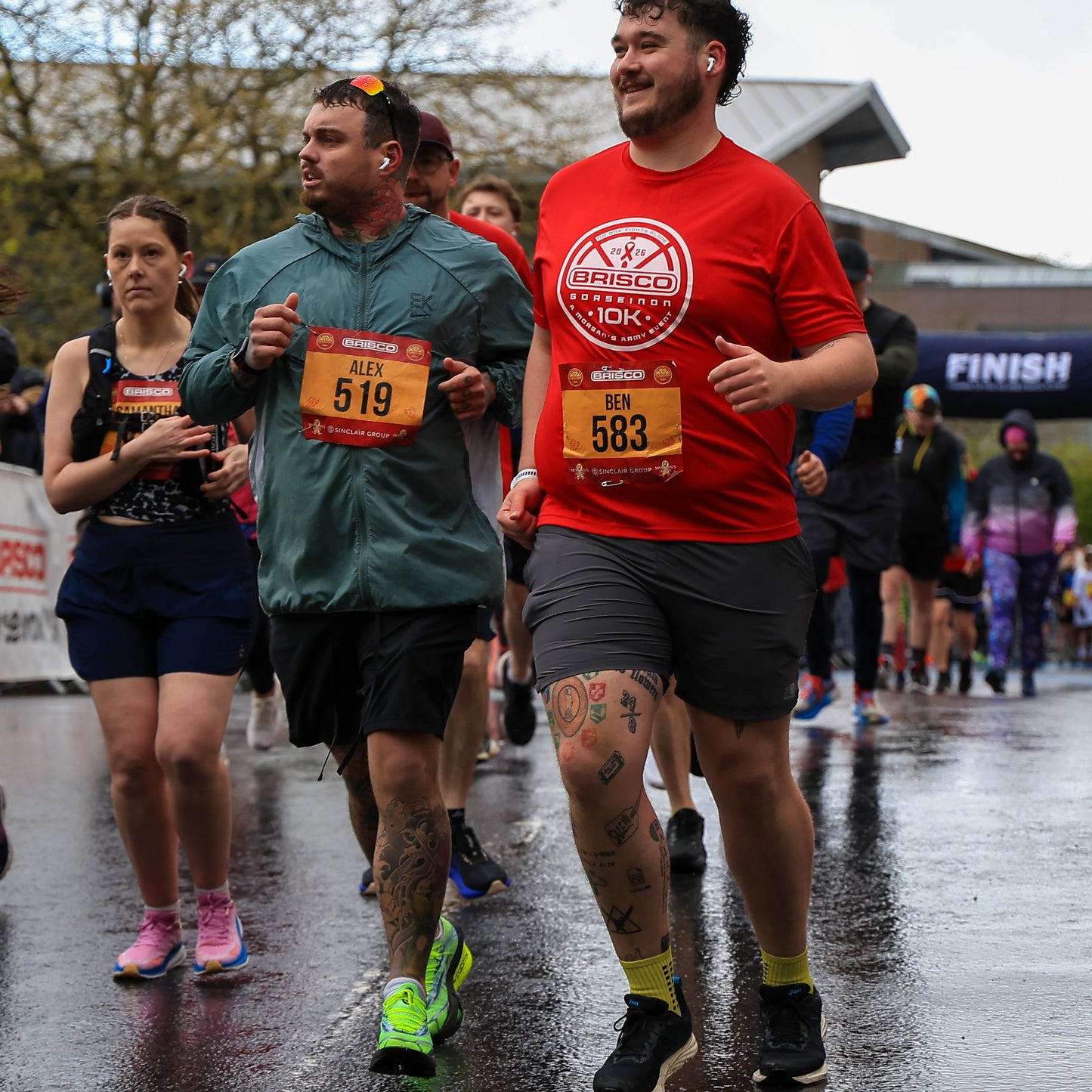 Runners participating in a race on a rainy day with visible race numbers.