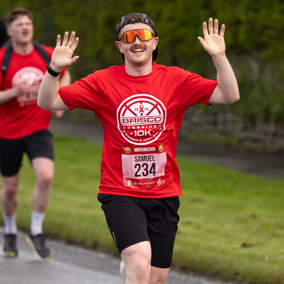 Man in a red Brisco race shirt with number 234 running outdoors.