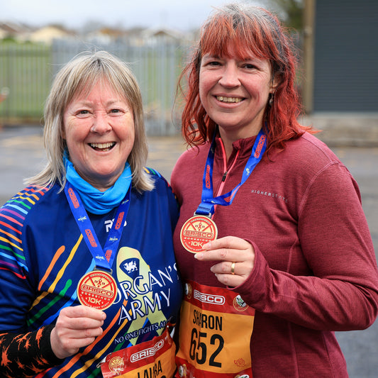Two women holding marathon medals in an outdoor setting