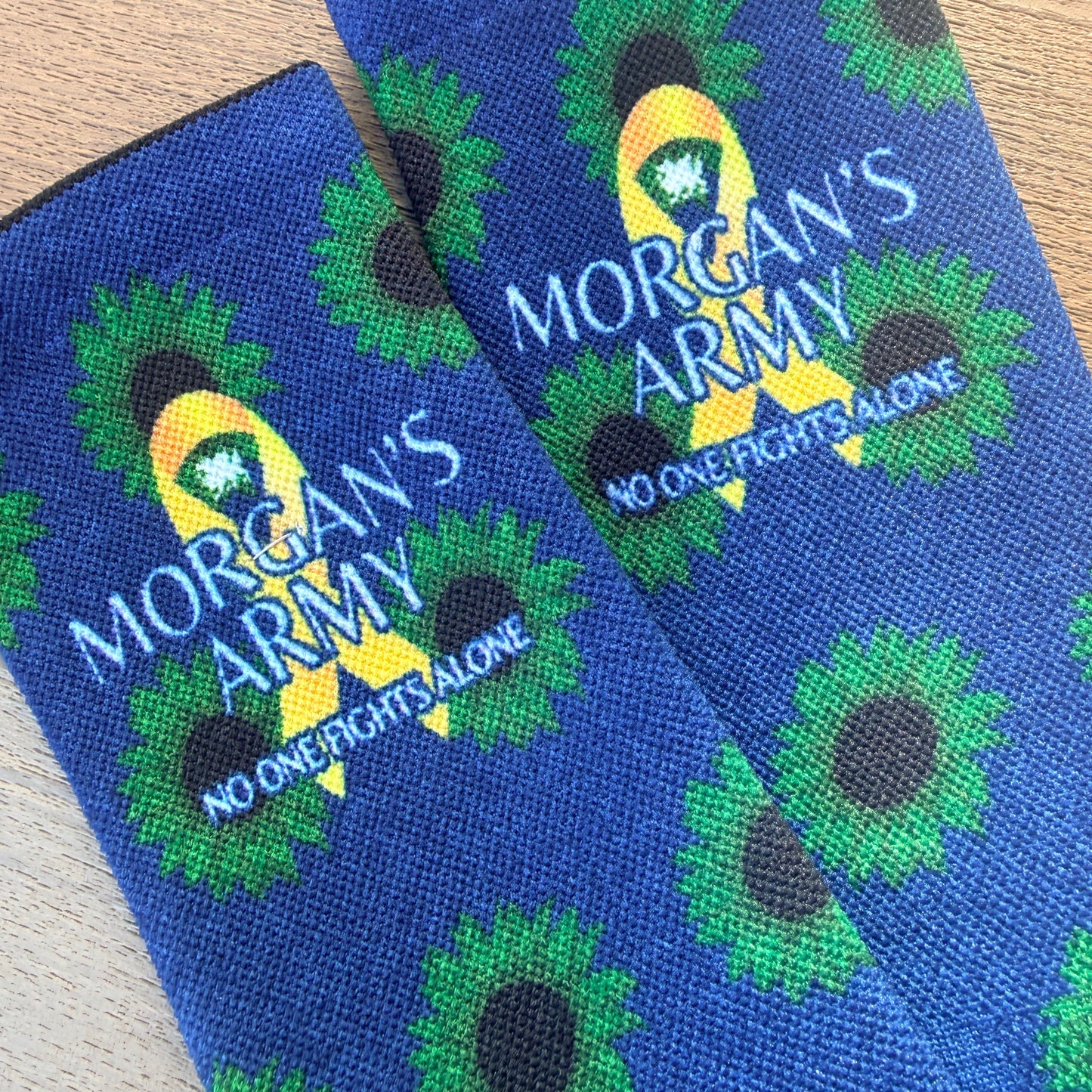 Blue socks with green floral patterns and 'Morgan's Army' branding on a wooden surface.